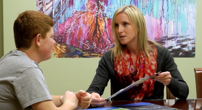 admissions counselor meeting with prospective student reviewing application and other materials